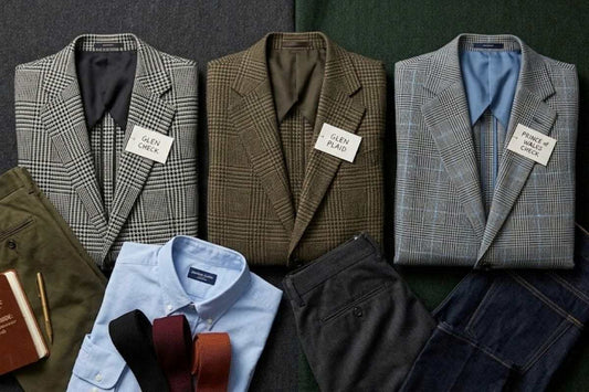 A vintage menswear flat lay demonstrating the styling differences between a monochromatic Glen Check, an earth-toned Glen Plaid, and a royal Prince of Wales check sport coat with a colored overcheck.