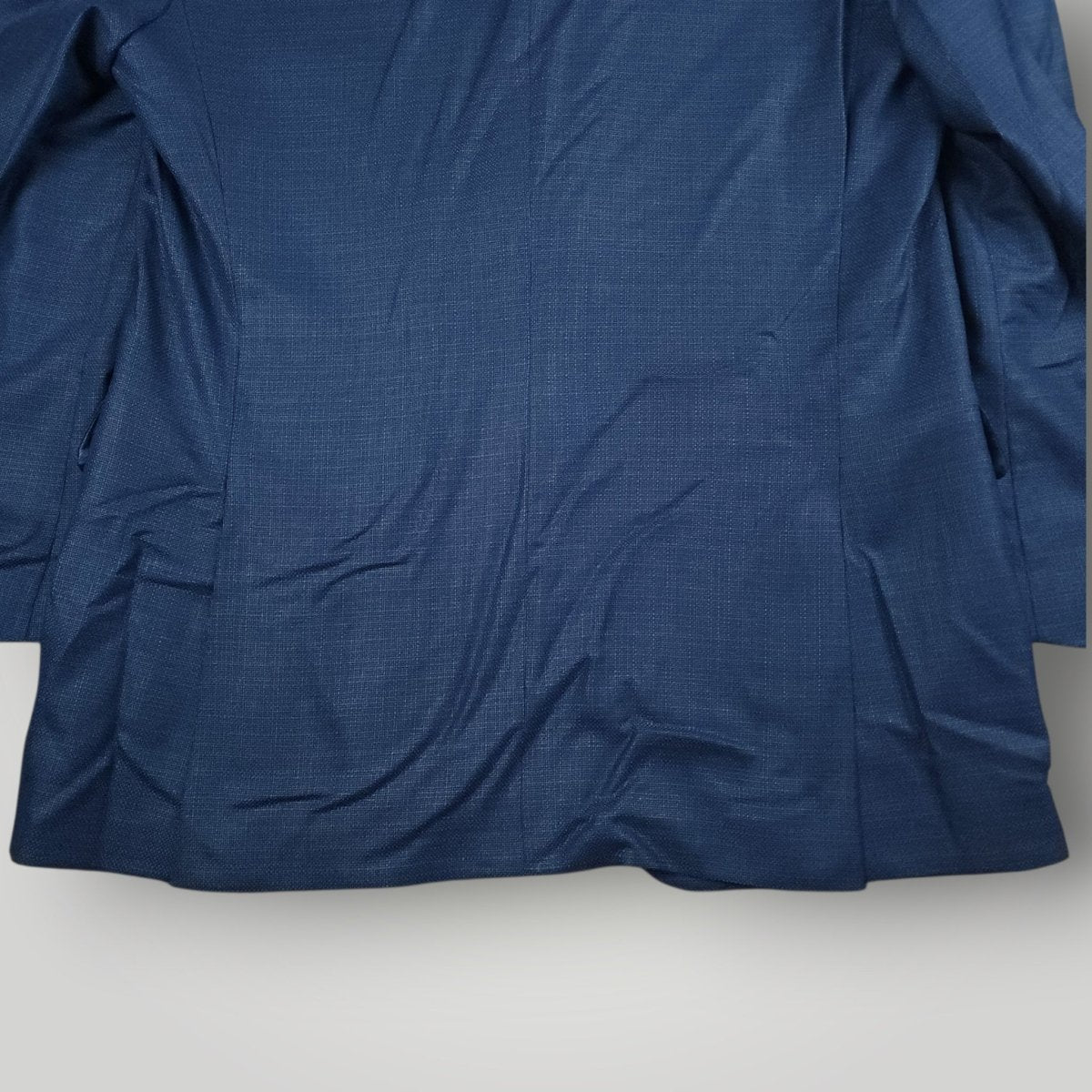 Rear lower view of blue Italian wool sport coat showing vent and hem detail.