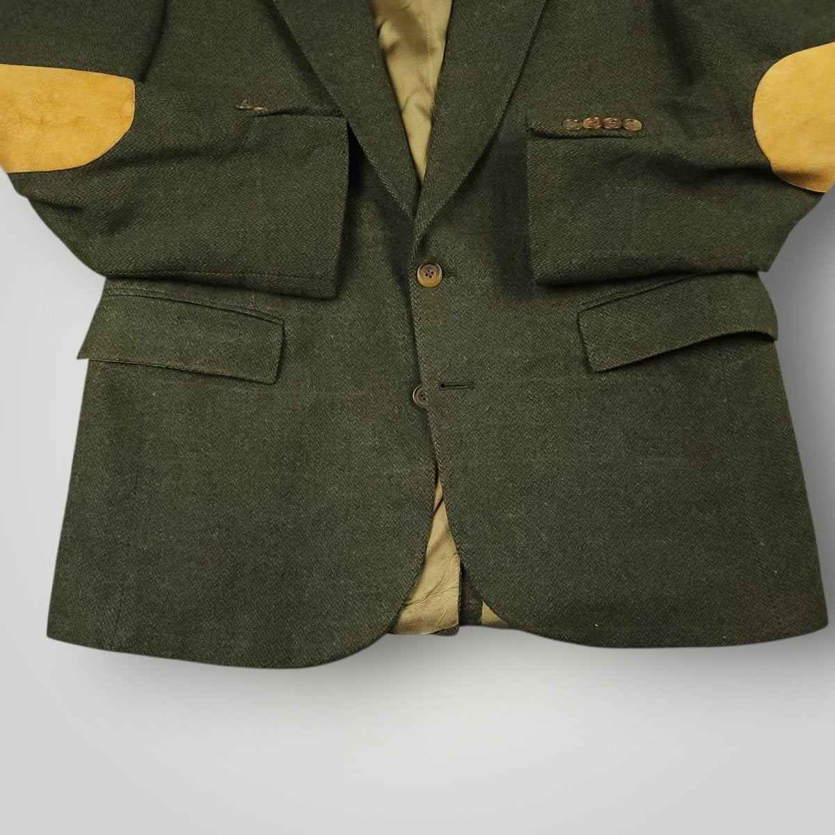Close up of flap pockets button stance and elbow patches on olive tweed blazer