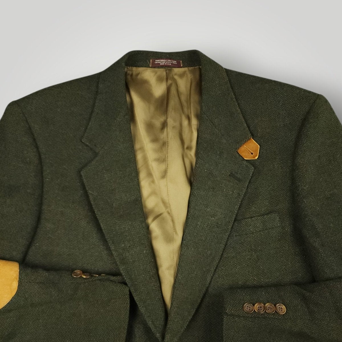 Close up view of olive tweed fabric and suede elbow patch detail