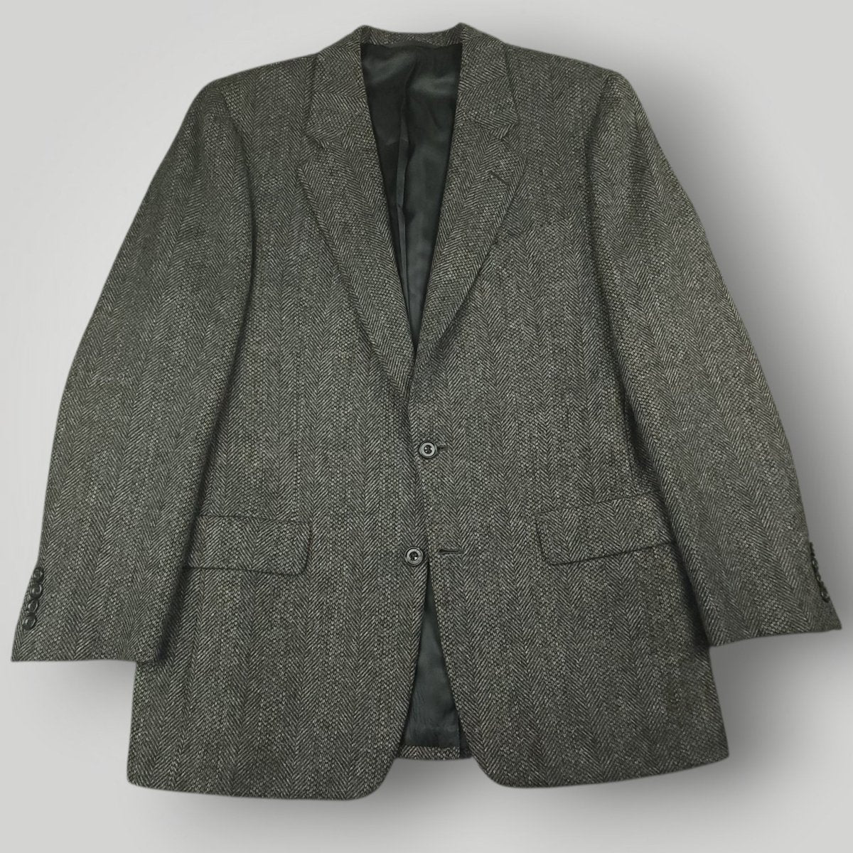 Gray herringbone tweed jacket with notch lapels, flap pockets, and two-button front