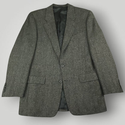 Gray herringbone tweed jacket with notch lapels, flap pockets, and two-button front
