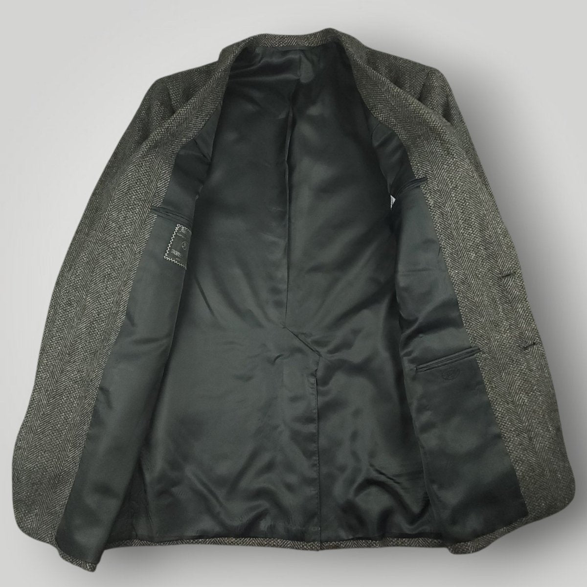 Interior view of a gray herringbone tweed jacket with black lining
