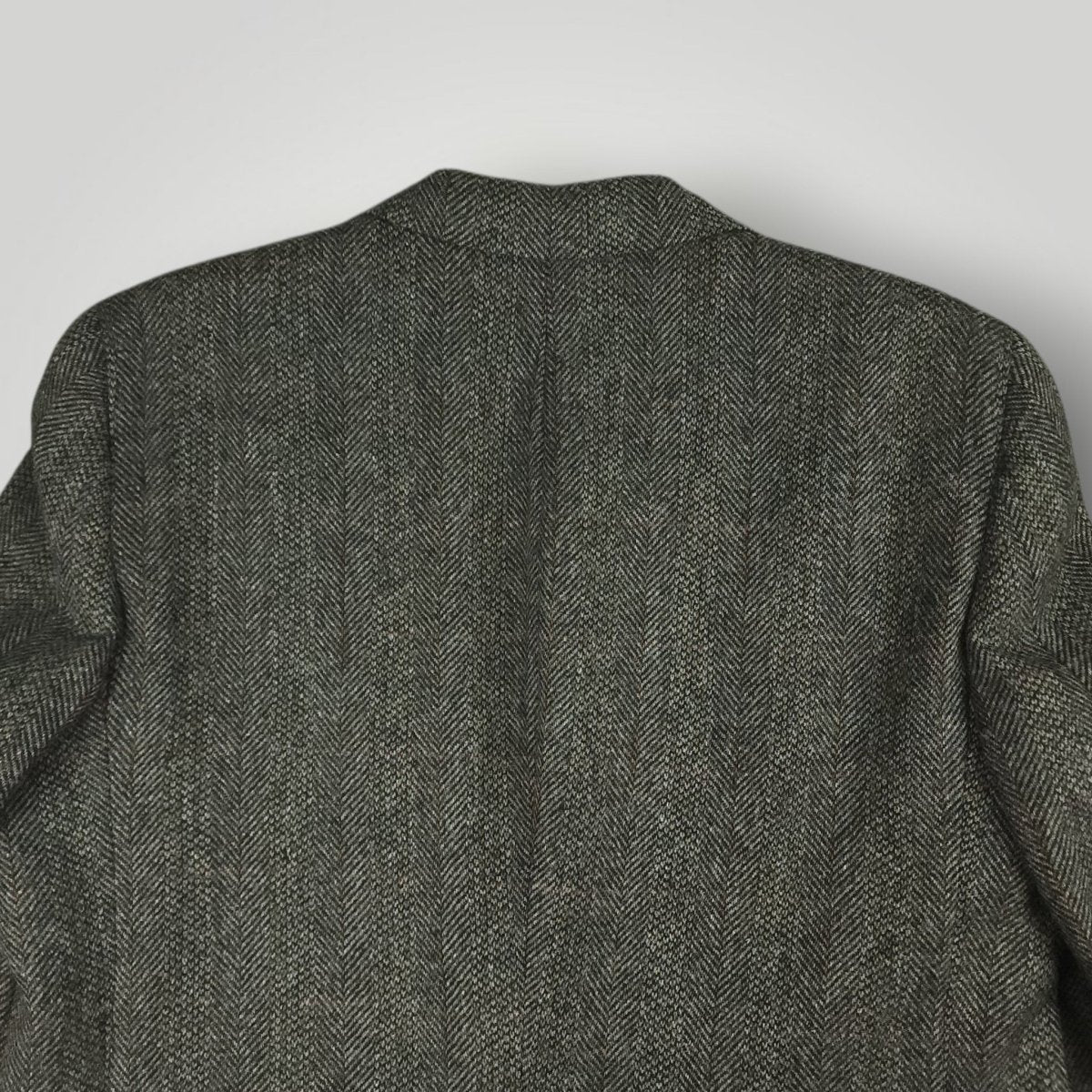 Back view of a gray herringbone tweed jacket showing the shoulder and collar area